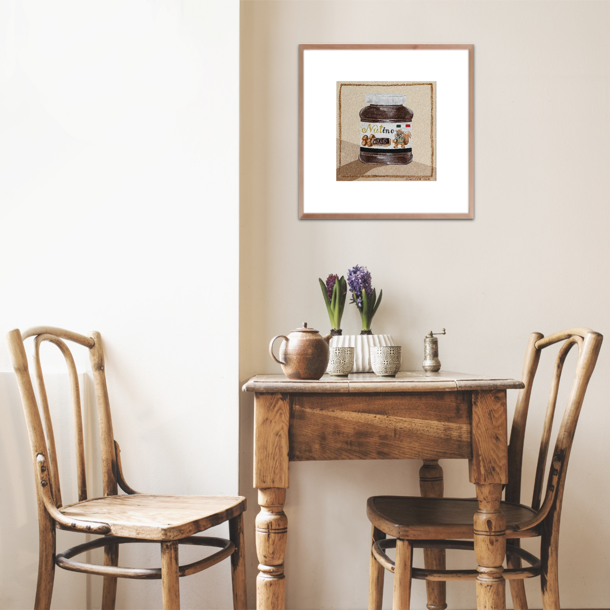 Nutino print by Marissa Lico. Small wooden table with two chairs against a wall, featuring a framed fine art print of Nutella above.