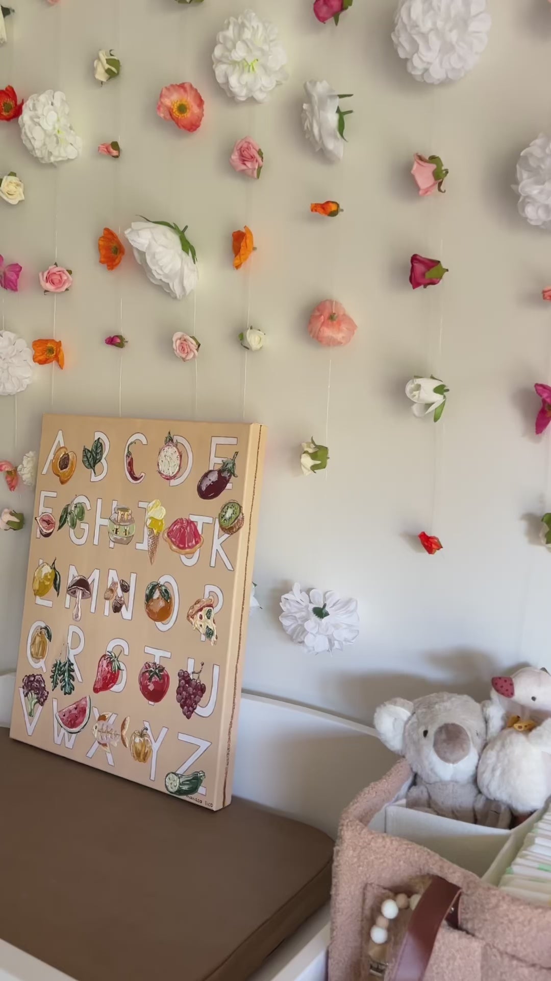 Alfabeto by Marissa Lico displayed in baby's nursery with hanging flower installation.