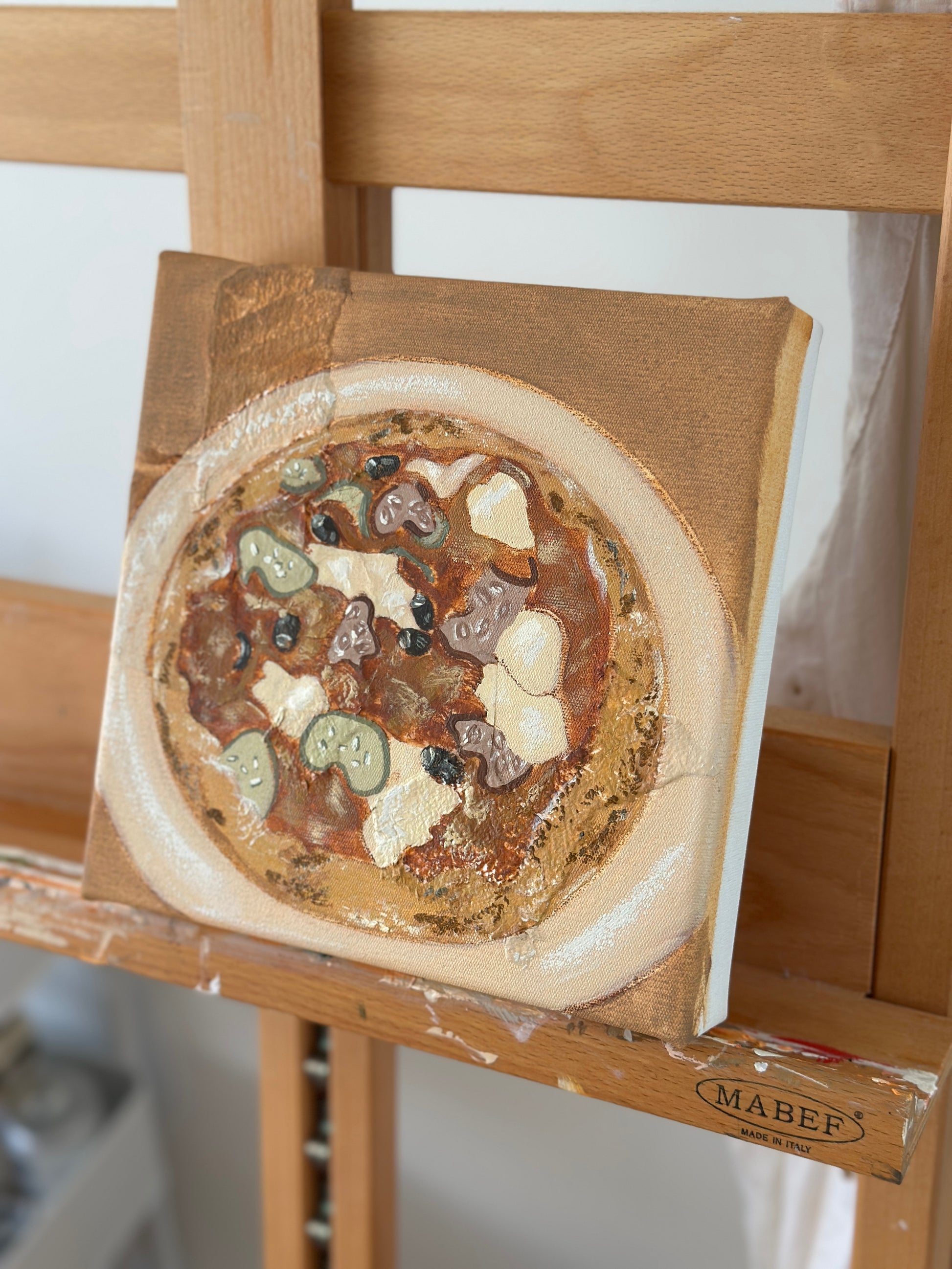 When In Italy painting of pizza by Marissa Lico. Small round painting on a wooden easel with 'Mabef' branding