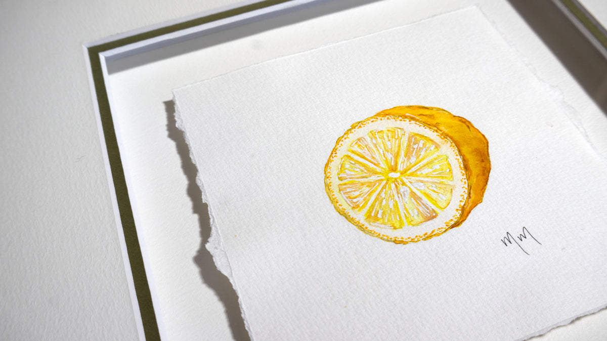 A square watercolor painting of a sliced lemon on textured white paper, mounted on a white mat board with a thin dark green matt edge visible. The painting is rendered in bright yellow tones with white highlights, and a small artist signature by Marissa Lico is visible in the lower right corner.