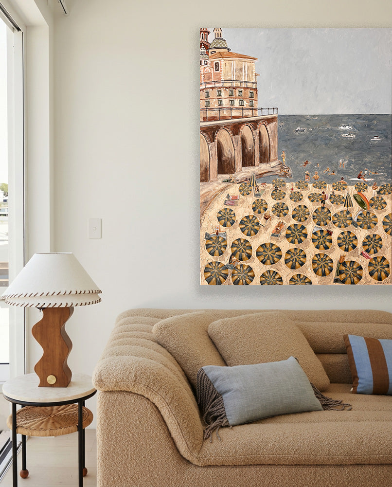 Al Mare, an original Amalfi Coast painting by Marissa Lico, hanging above a cream bouclé sofa in a sunlit, neutral living room.