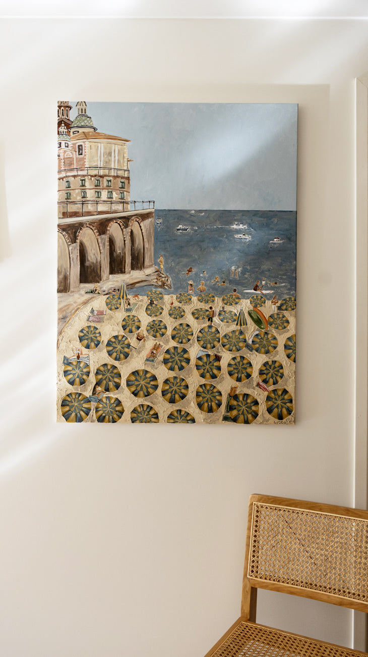Al Mare original Amalfi Coast painting by Marissa Lico displayed on a wall in dining a room, showing striped beach umbrellas and the Italian coastline.